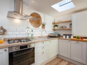 a kitchen with white cabinets and a sink at Delius in Penryn