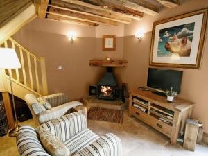 a living room with a television and a fireplace at Cornstore Cottage in Highpeak Junction