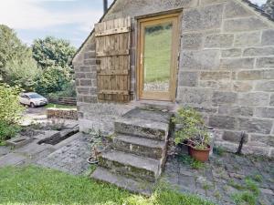 a stone house with a door and some stairs at Cornstore Cottage in Highpeak Junction