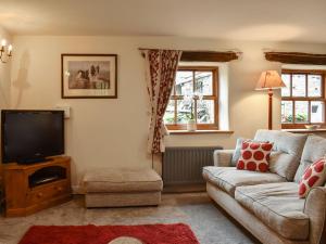 a living room with a couch and a tv at Beck Foot Cottage in Sedbergh