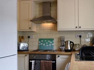 a kitchen with white cabinets and a stove top oven at Archies Cottage in Burnmouth