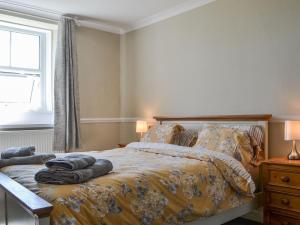 a bedroom with a bed with blankets and a window at Fieldside Farmhouse in Tallentire