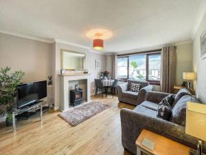 a living room with a couch and a television at Laroch Cottage in Ballachulish