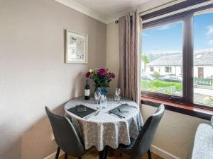 a table with chairs and a vase of flowers on it at Laroch Cottage in Ballachulish