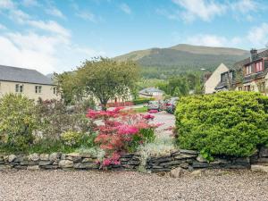 a garden with pink flowers and a stone wall at Laroch Cottage in Ballachulish