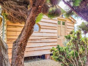 ein Holzgebäude mit einer Tür neben einem Baum in der Unterkunft Walnut Lodge in Wells