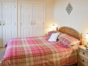 a bedroom with a bed with a plaid blanket at Heckley Cottage in Alnwick