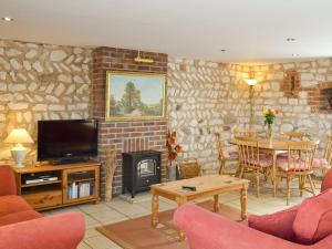 ein Wohnzimmer mit einem TV, einem Tisch und einem Kamin in der Unterkunft Seagull Cottage in Flamborough