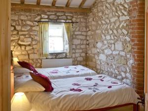 a bedroom with two beds and a stone wall at Seagull Cottage in Flamborough