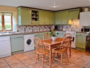 a kitchen with green cabinets and a wooden table and chairs at Blackberie Cottage - E2389 in Stoke Abbott