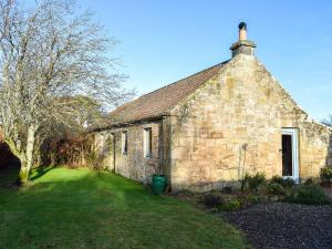 an old stone building with a grass yard in front of it at The Outside Room in Ladybank