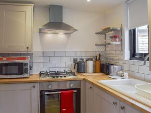 a kitchen with a stove top oven next to a sink at Badgers Sett Brook in Brook