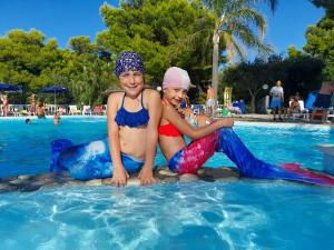 dos chicas sentadas en el agua en una piscina en Residence Emarine en Peschici