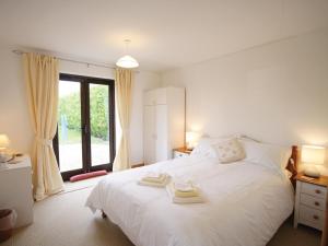 a bedroom with a white bed and a large window at High Farm Barn in Brisley