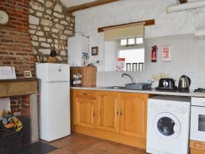 uma cozinha com um frigorífico branco e uma máquina de lavar e secar roupa em Guillemot Cottage em Flamborough