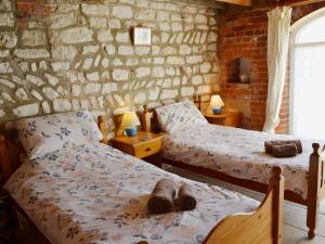 a bedroom with two beds and a brick wall at Guillemot Cottage in Flamborough