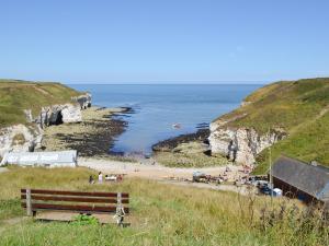 um banco sentado numa colina ao lado de uma praia em Guillemot Cottage em Flamborough