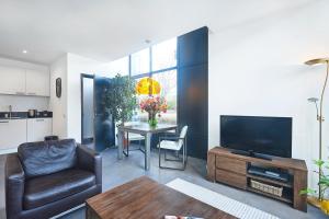 ein Wohnzimmer mit einem Tisch, einem TV und einem Sofa in der Unterkunft Blush Appartement Centrum Middelburg in Middelburg