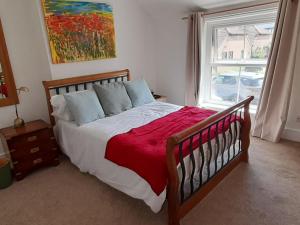 ein Schlafzimmer mit einem Bett mit einer roten Decke und einem Fenster in der Unterkunft Willow Cottage in Stockbridge
