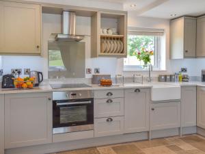 a kitchen with white cabinets and an oven at Gwynfa - Uk39366 in Frongoch