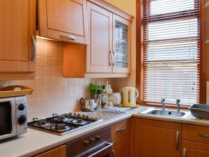 una cucina con armadi in legno, piano cottura e lavandino di The Aul Bank a Whitehills