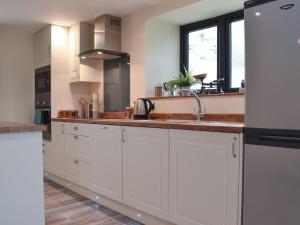 uma cozinha com armários brancos e um lavatório em The Stable em Bridgwater