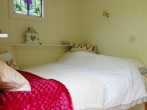 a bedroom with a white bed with a red blanket at Beunos Hut -ukc4752 in Tremeirchion