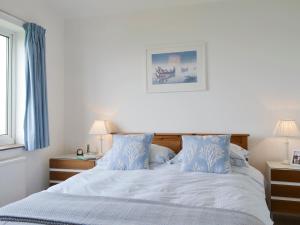 a white bed with blue pillows in a bedroom at West Lawn in Rhosneigr