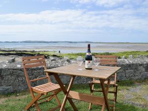 a table with a bottle of wine and two chairs at West Lawn in Rhosneigr