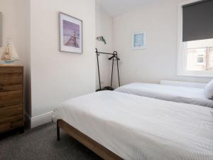 a bedroom with two beds and a dresser and a window at Sea Haven in Woodhorn