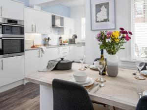 a kitchen with a wooden table with a vase of flowers at Sea Haven in Woodhorn