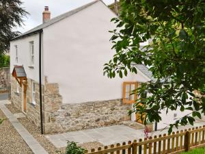 a white cottage with a stone wall and a fence at Penny Cottage - Tof in Par