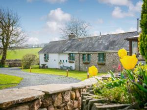 a stone cottage with a stone wall and yellow flowers at Teal in Llangennith