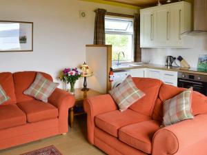 a living room with two orange couches and a kitchen at Cuillin View in Husabost