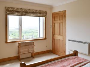 a bedroom with a window and a bed with a window seat at Cuillin View in Husabost