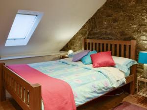 Un dormitorio con una cama con almohadas de colores. en The Pig Sty, en Llanfair-ar-y-bryn