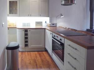 uma cozinha com armários brancos e um balcão de madeira em Tuppence Cottage em Dulverton