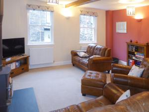 a living room with leather furniture and a flat screen tv at Tuppence Cottage in Dulverton
