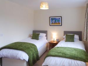 a bedroom with two beds with green blankets at Tuppence Cottage in Dulverton