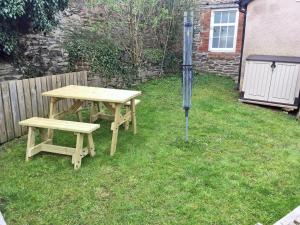a picnic table and two benches in a yard at Tuppence Cottage in Dulverton