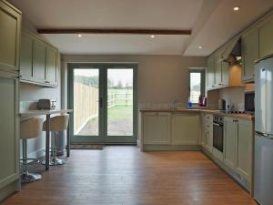a kitchen with green cabinets and a large window at Waxwing Cottage in Foxton