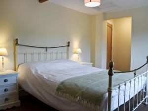 a bedroom with a bed and a nightstand with two lamps at Waxwing Cottage in Foxton