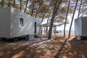 a gray tiny house with a gazebo and trees at Camping&Village Le Cernie in Lotzorai
