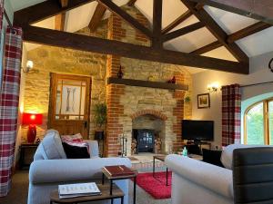 una sala de estar con sofás y una chimenea de piedra. en Rivers Edge Cottage en Shotley Bridge