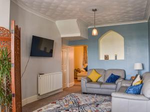 uma sala de estar com um sofá e uma televisão em Ocean View Cottage em Burry Port