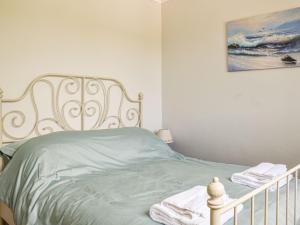 um quarto com uma cama com lençóis verdes e um quadro em Ocean View Cottage em Burry Port