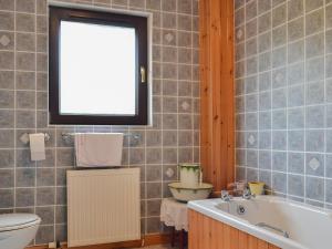 a bathroom with a tub and a toilet and a window at Sealladh Lingeigh in Pollachar