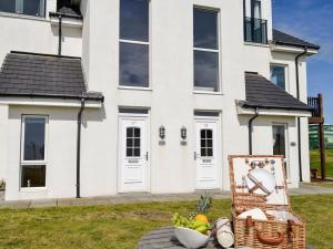 una casa bianca con un cesto di frutta di fronte di Seaviews And Hot Tub At The Fairways - Uk39821 a Portpatrick