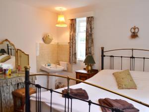 a bedroom with a bed and a bathroom with a sink at Apple Tree Cottage in West Wittering