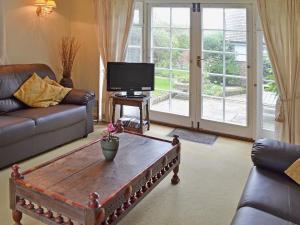 a living room with a coffee table and a tv at Apple Tree Cottage in West Wittering